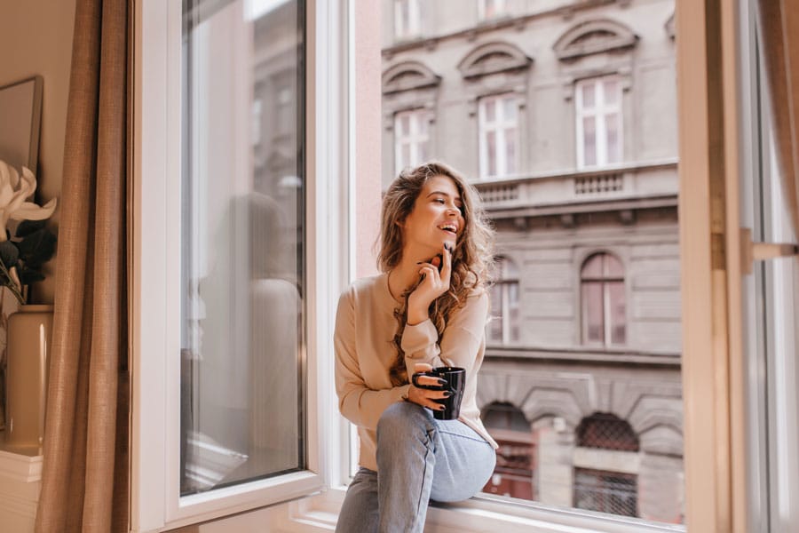 adorable-young-woman-trendy-jeans-enjoying-leisure-time-home-with-cup-hot-chocolate